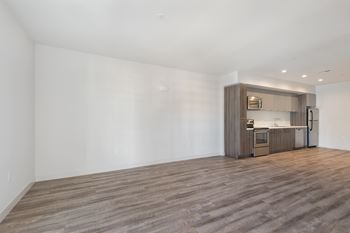 A kitchen area with a wooden floor and a white wall.